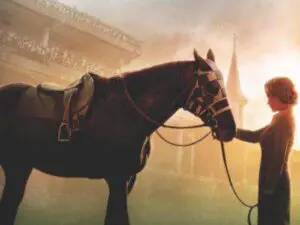 Person leading saddled horse near racetrack