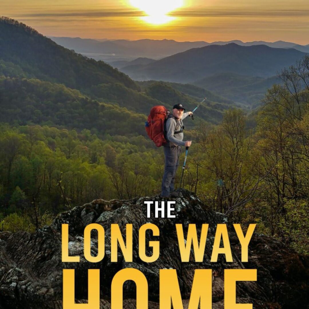 Hiker with backpack on mountain ridge at sunset