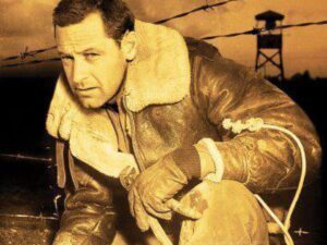 Man in aviator jacket crouching by barbed wire