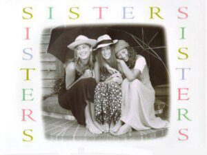 Three sisters sitting together under umbrella
