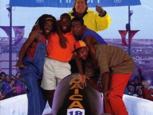 Group posing with bobsled under finish banner