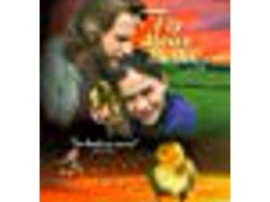 Two people smiling over chick in grassy field